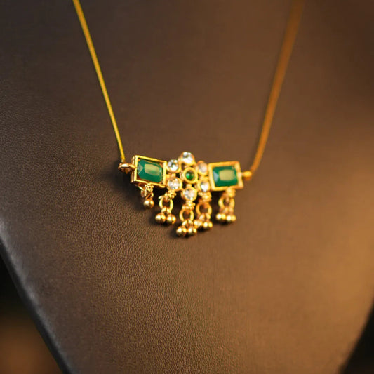 Gold necklace with green gemstones on a dark background