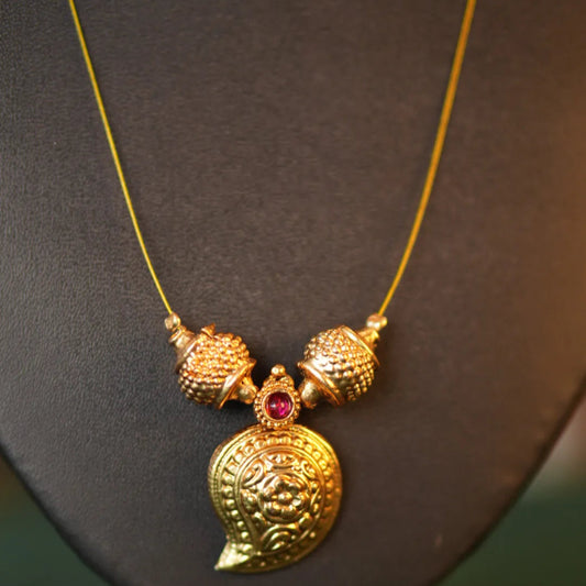 Gold necklace with a pendant on a black stand