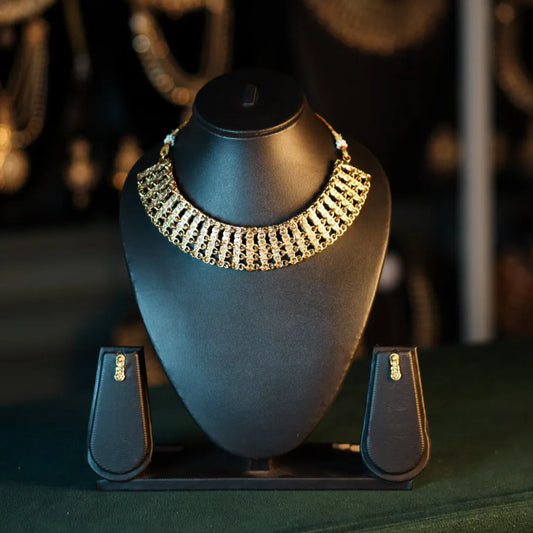 Gold necklace on a black mannequin bust with a blurred jewelry store background
