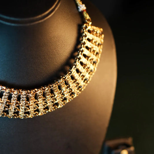 Gold necklace on a black mannequin bust with a dark background