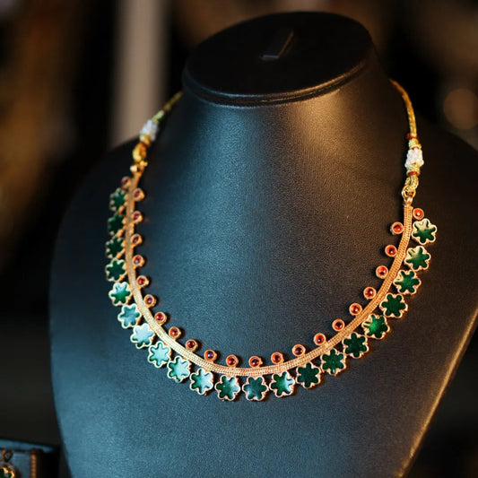 Gold and green necklace on a mannequin bust with blurred background