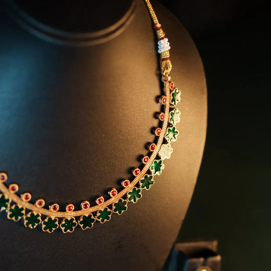 Gold necklace with green accents on a dark background
