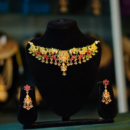 Gold necklace and earrings set on a black stand with blurred background