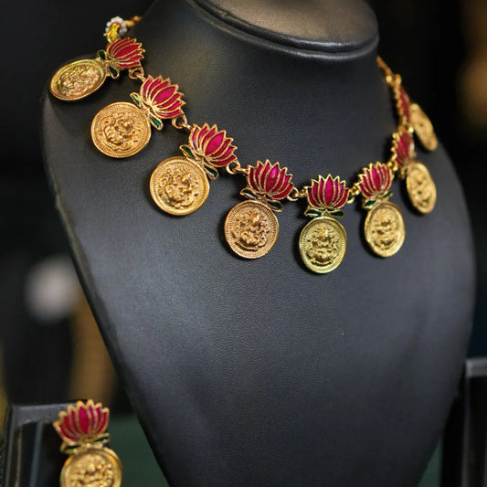 Gold and red necklace on a black mannequin bust with blurred background