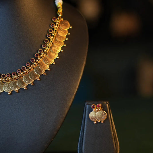 Gold necklace and earrings on a dark background