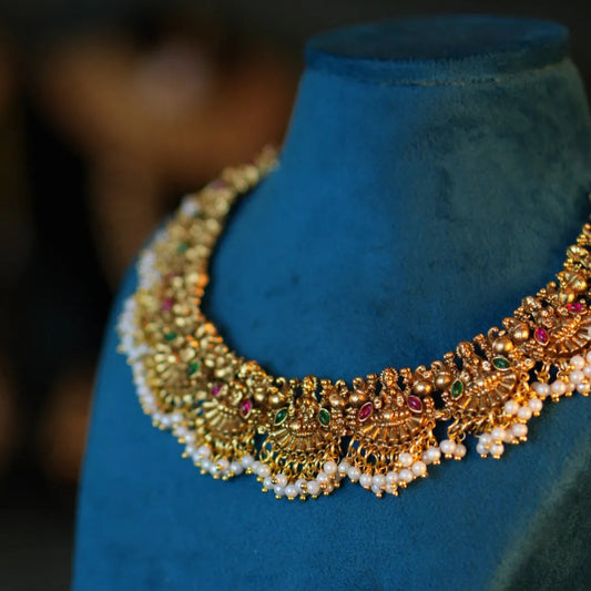 Gold necklace with pearls on a blue mannequin