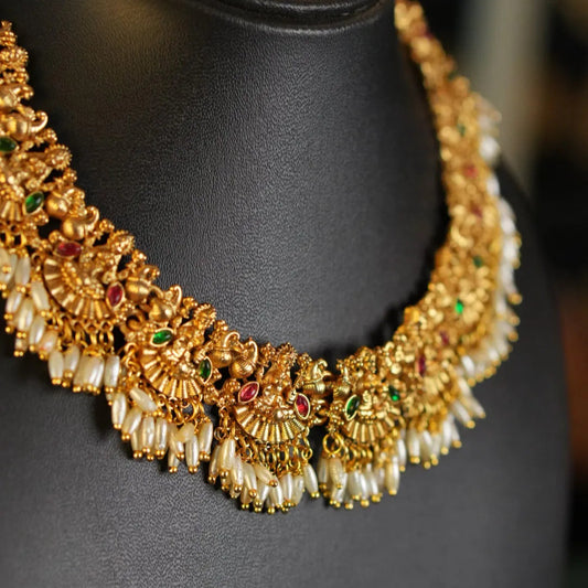 Gold necklace with pearls and gemstones on a black mannequin