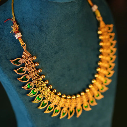 Gold necklace with green gemstones on a blue mannequin
