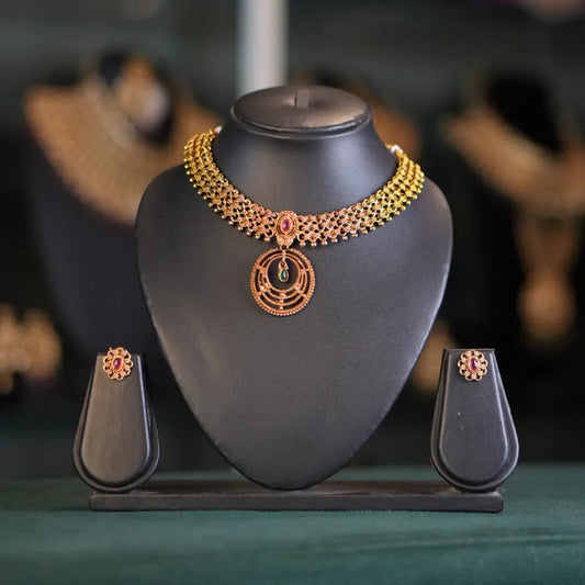 Gold necklace on a black stand with a blurred jewelry store background