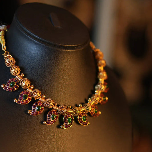 Gold necklace with colorful gemstones on a mannequin bust.