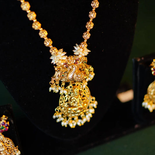 Gold necklace with intricate design on a dark background