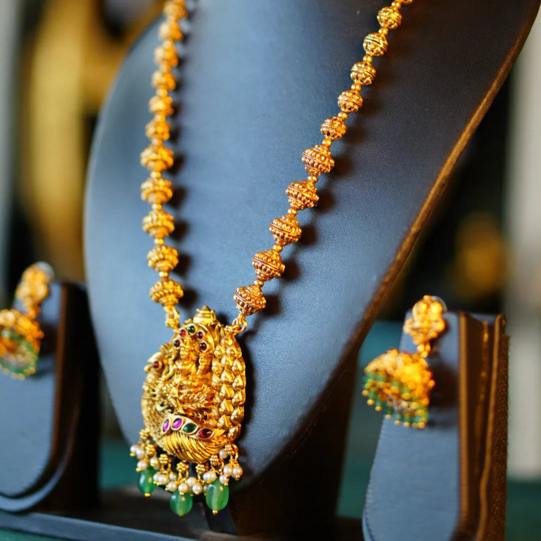 Gold necklace with green gemstones on a mannequin bust