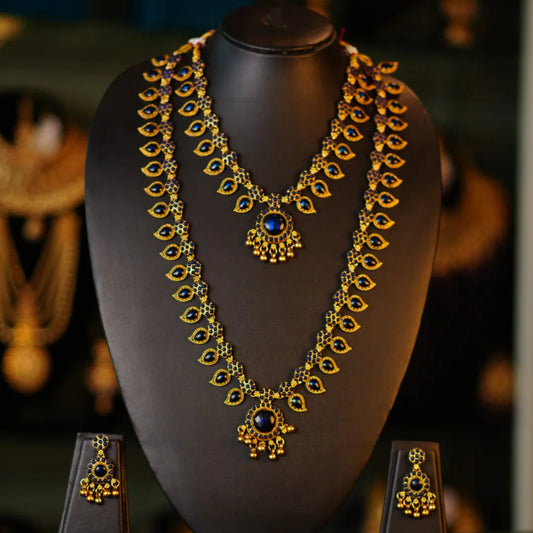Ornate necklace and earrings set on a black mannequin bust with a blurred background
