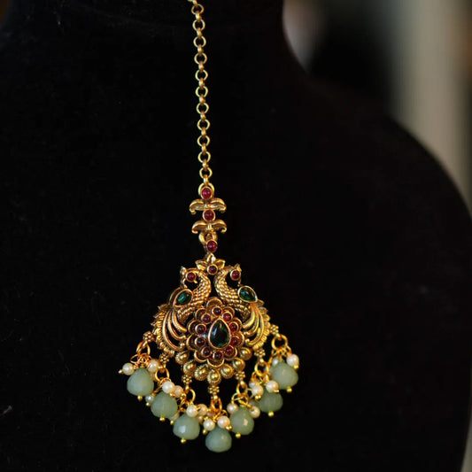 Gold and green gemstone pendant on a black background