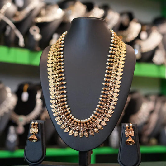 Gold necklace on a black stand with blurred jewelry store background