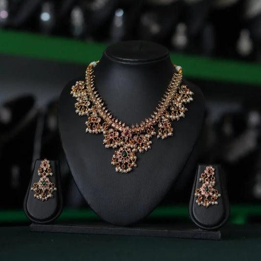 Jewelry set with necklace and earrings on a black stand against a blurred background