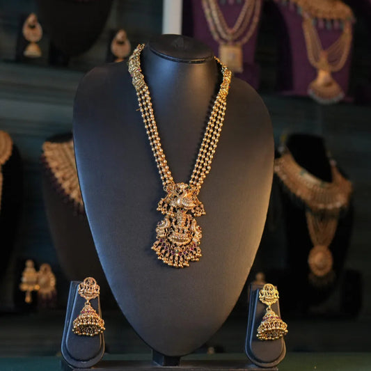 Gold necklace and earrings on a black mannequin bust with a dark background